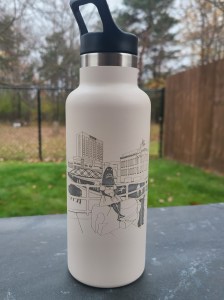 Photograph of engraved tumbler outside. Tumbler is engraved with a scene Canalside in Buffalo, NY.
