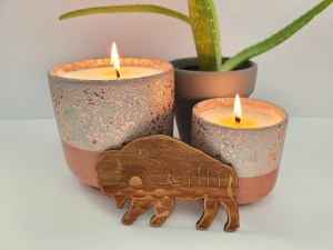 Photograph of Wooden Buffalo Magnet with candles and plant in the background