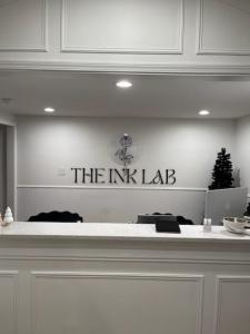 Photograph of Custom Acrylic signage - 1/4" with hidden standoffs for mounting. Reads "The Ink Lab" with their rose logo