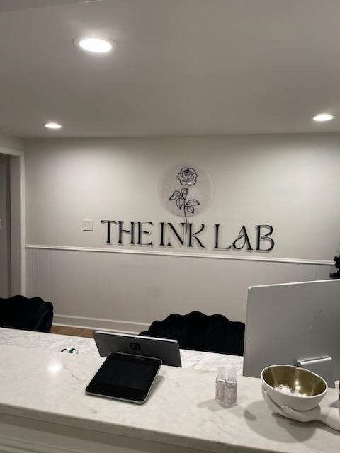 Photograph of Custom Acrylic signage - 1/4" with hidden standoffs for mounting. Reads "The Ink Lab" with their rose logo
