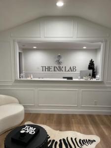 Photograph of Custom Acrylic signage - 1/4" with hidden standoffs for mounting. Reads "The Ink Lab" with their rose logo
