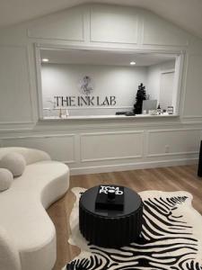 Photograph of Custom Acrylic signage - 1/4" with hidden standoffs for mounting. Reads "The Ink Lab" with their rose logo