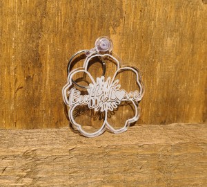 Photograph of clear acrylic violet (flower) keychain against wooden background.